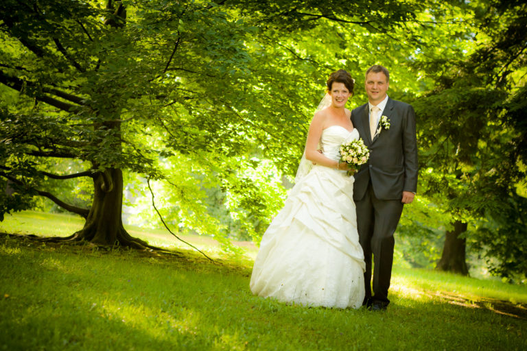 Portrét novomanželů v&nbsp;zeleném parku během svatebního dne